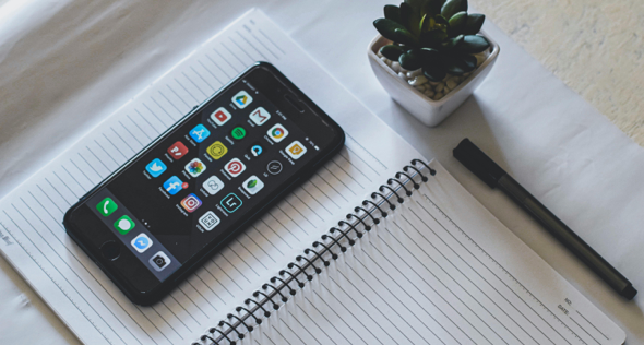 A smartphone and notebook on a table.